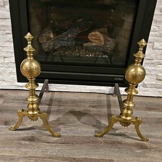 Antique brass and iron ornate fireplace andirons used as decorative hearth log holders.