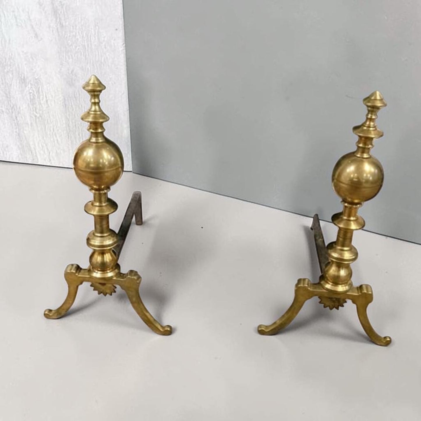Antique brass and iron ornate fireplace andirons used as decorative hearth log holders.