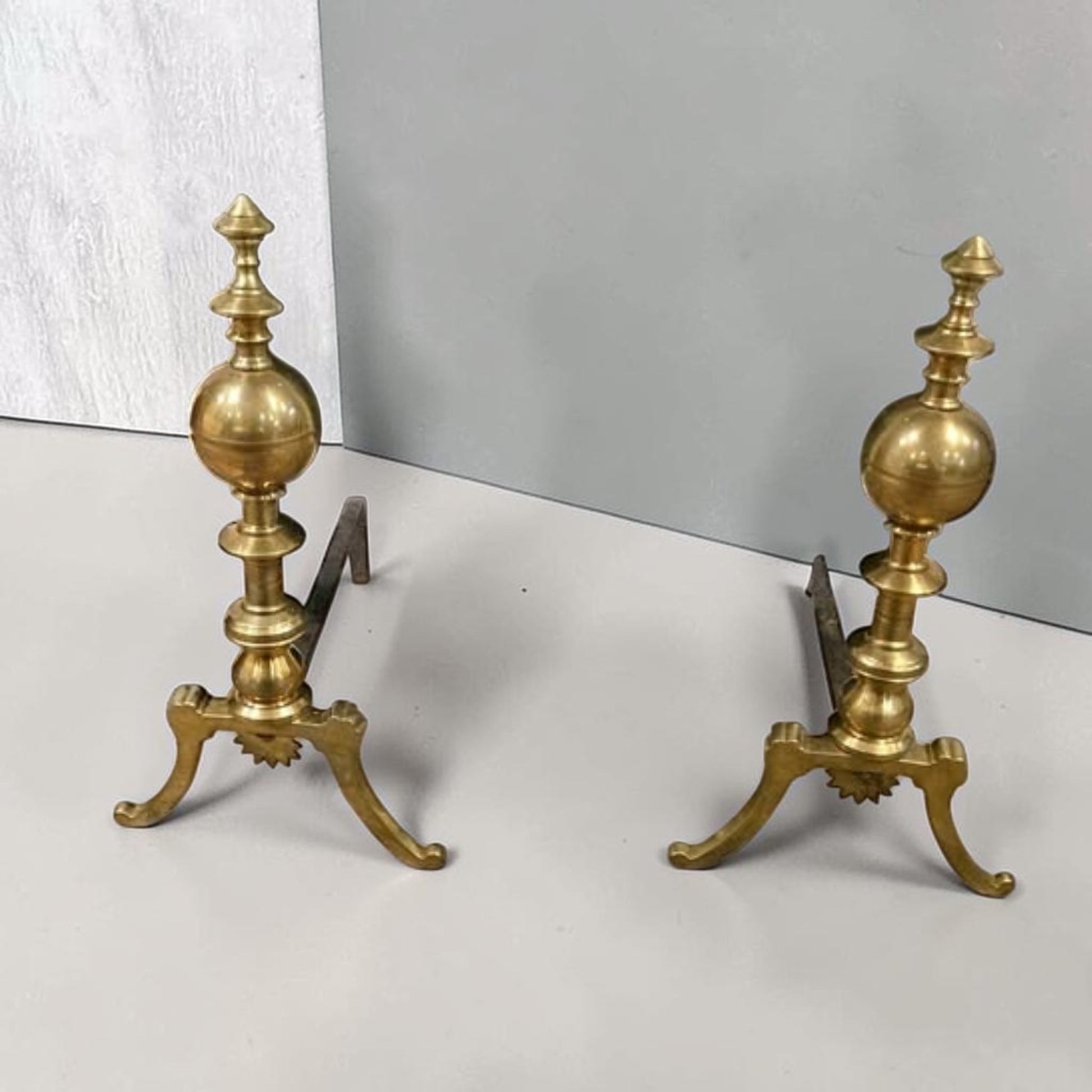 Antique brass and iron ornate fireplace andirons used as decorative hearth log holders.
