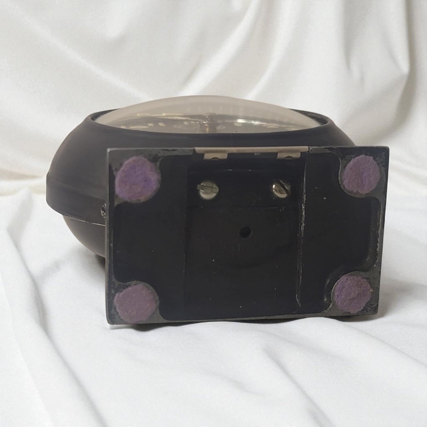Black rectangular object with purple circular patterns on a white fabric background