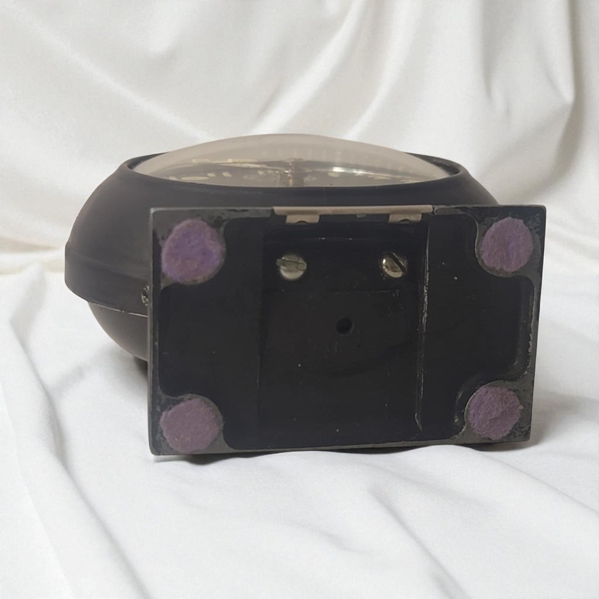 Black rectangular object with purple circular patterns on a white fabric background