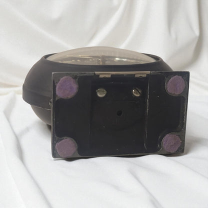 Black rectangular object with purple circular patterns on a white fabric background