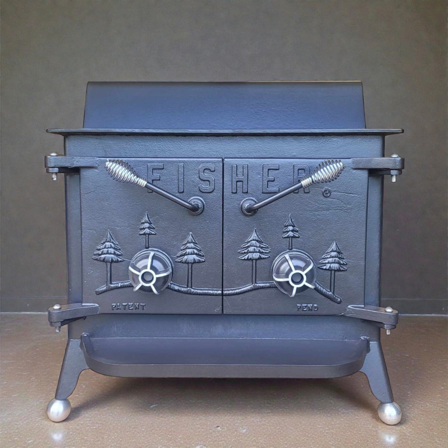 Cast iron stove with 'Fisher' branding and design on a gray background