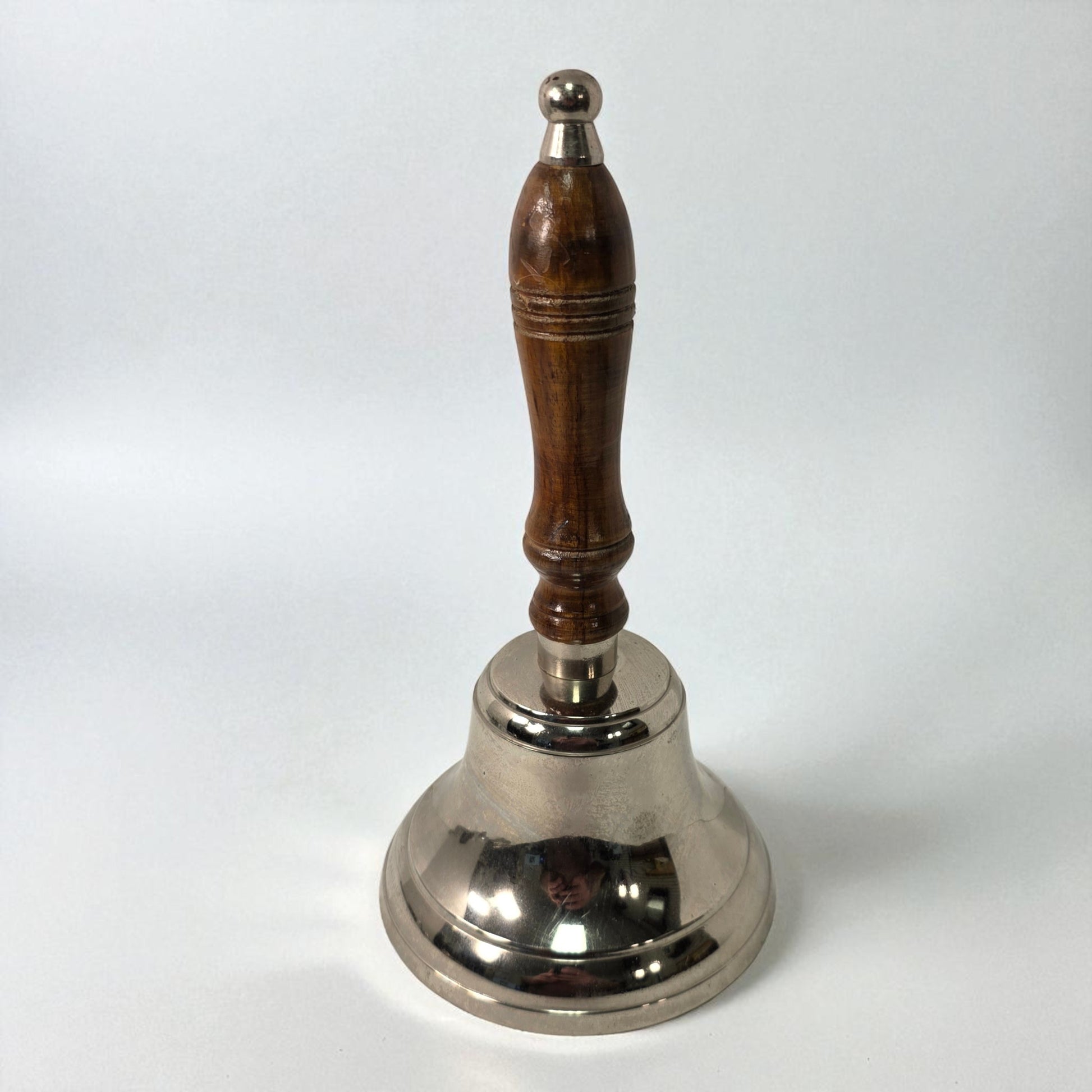 Silver bell with a wooden handle on a white background