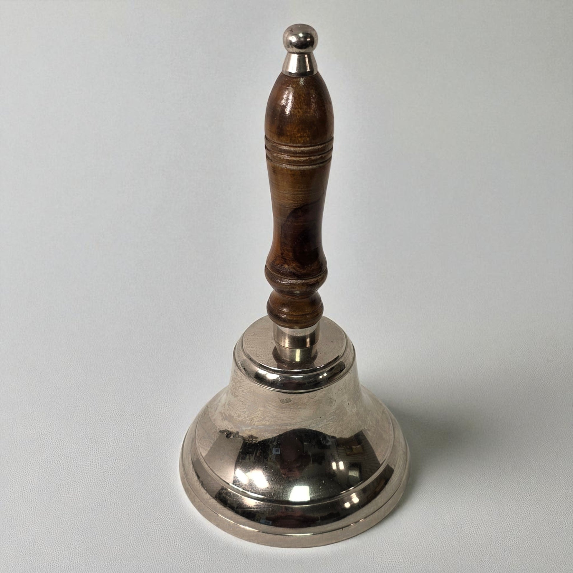 Silver bell with a wooden handle on a white background