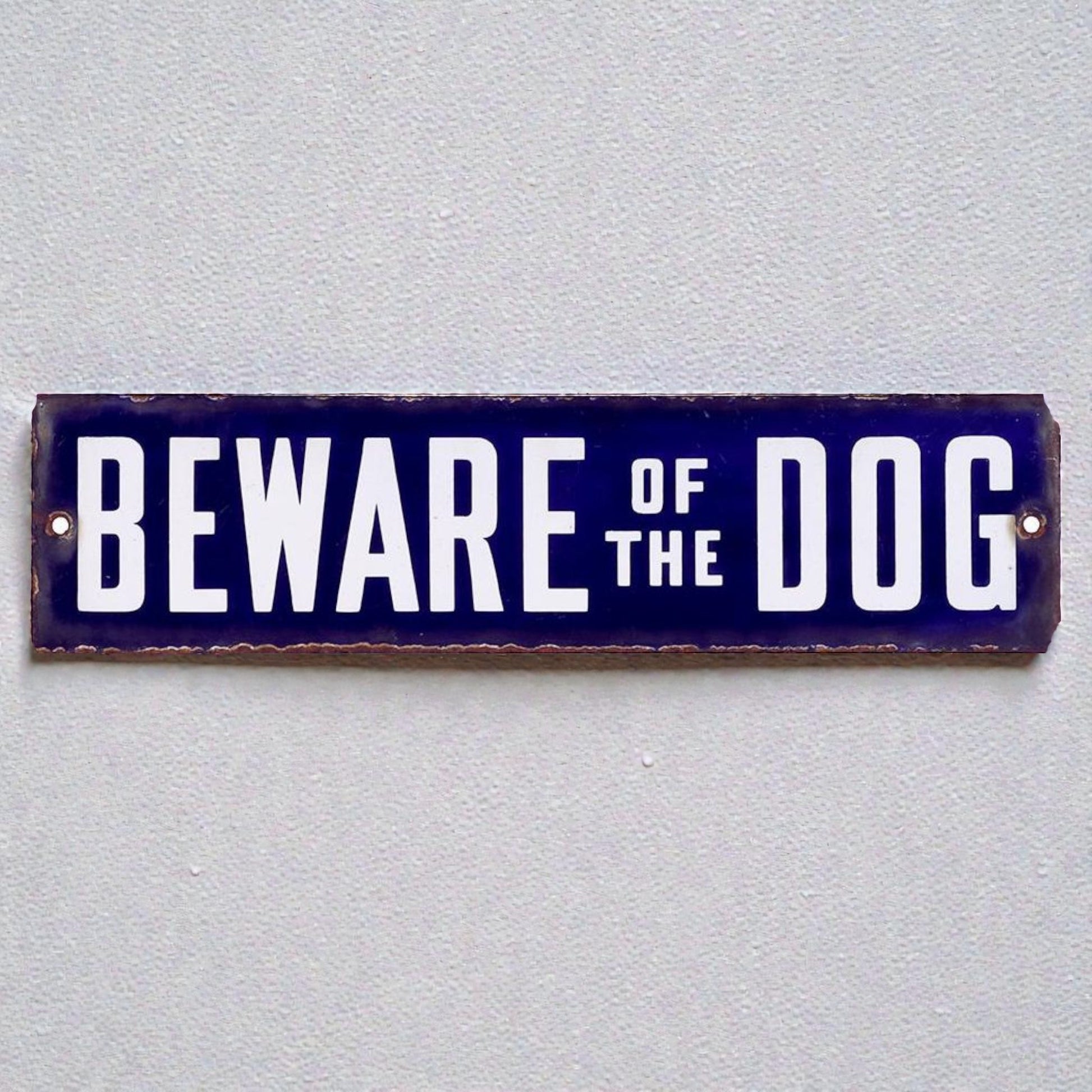metal sign with 'Beware of the Dog' text on a gray background