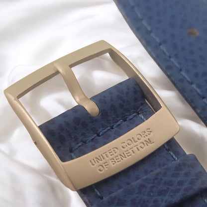 Close-up of a blue watch strap with gold buckle on a white background