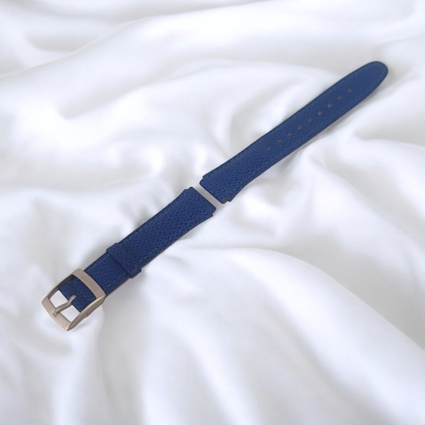 Blue watch strap with silver buckle on a white background