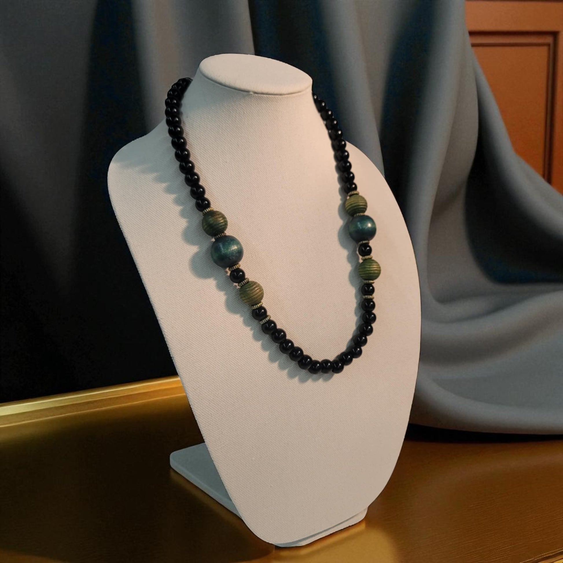 Necklace with black and green beads on a white mannequin bust against a neutral background