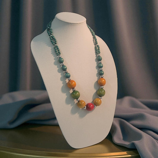 Necklace with multicolored beads on a white mannequin bust against a gray curtain background