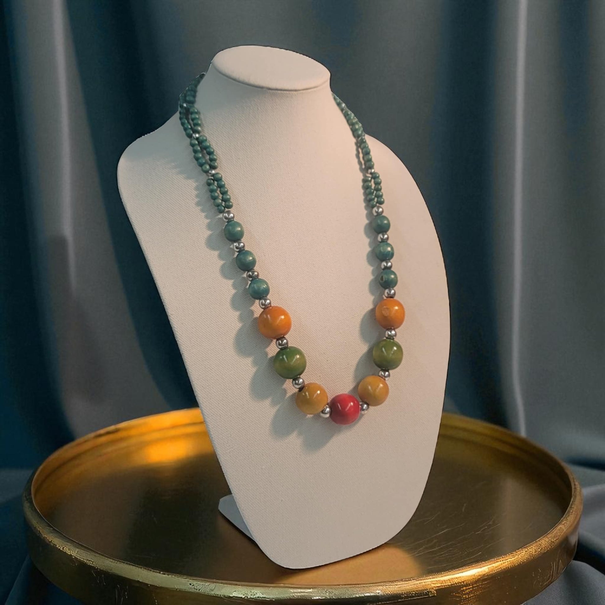 Necklace with multicolored beads on a white bust against a dark curtain background