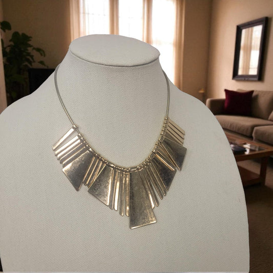 Gold necklace on a mannequin bust with a blurred indoor setting