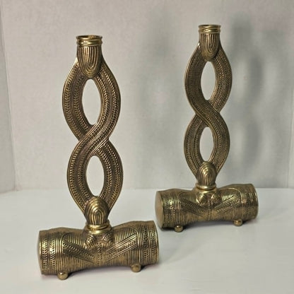 Pair of brass figure-eight candle holders with Egyptian-style engraved detailing.