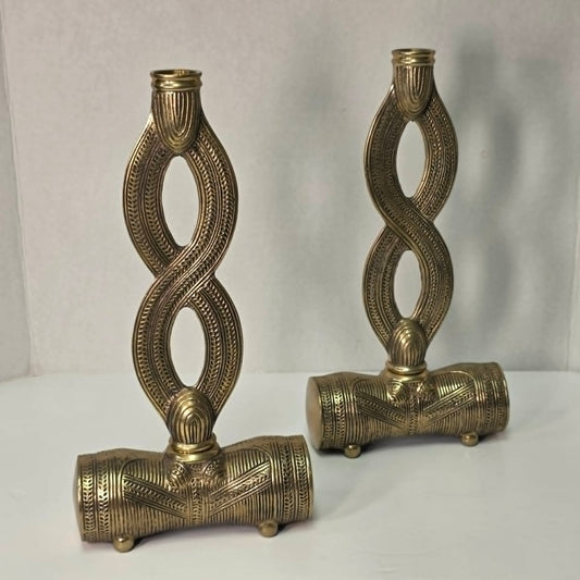 Pair of brass figure-eight candle holders with Egyptian-style engraved detailing.