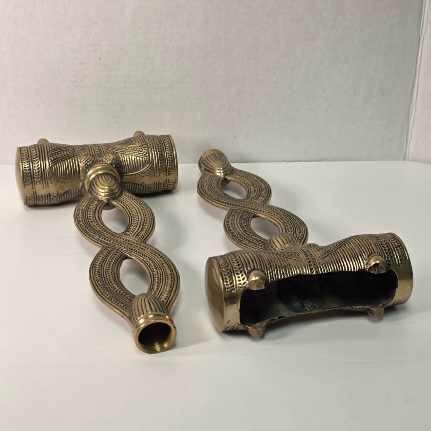 Pair of brass figure-eight candle holders with Egyptian-style engraved detailing.