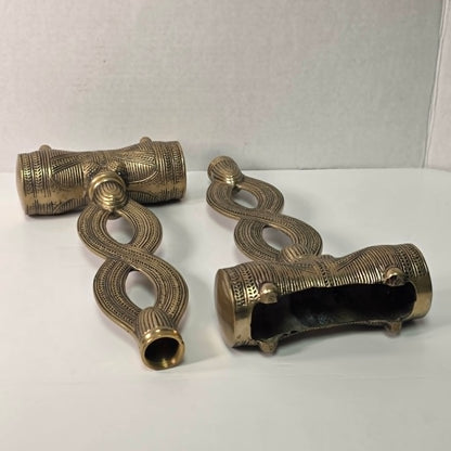 Pair of brass figure-eight candle holders with Egyptian-style engraved detailing.