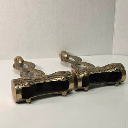 Pair of brass figure-eight candle holders with Egyptian-style engraved detailing.