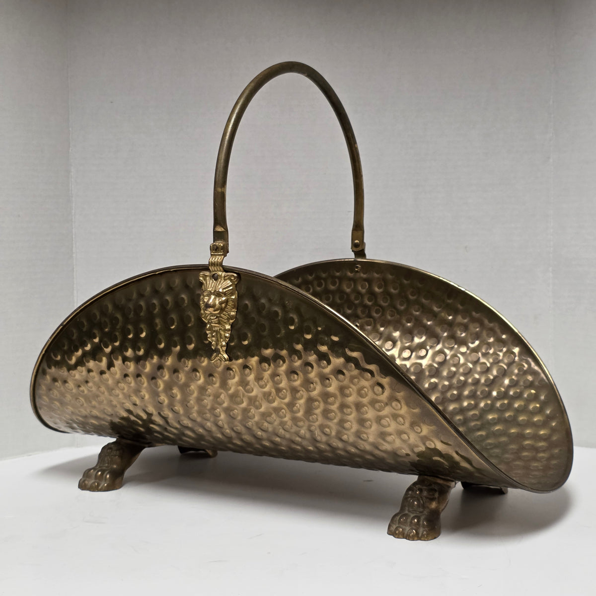 Ornate brass fireplace log holder with lion heads and paw feet
