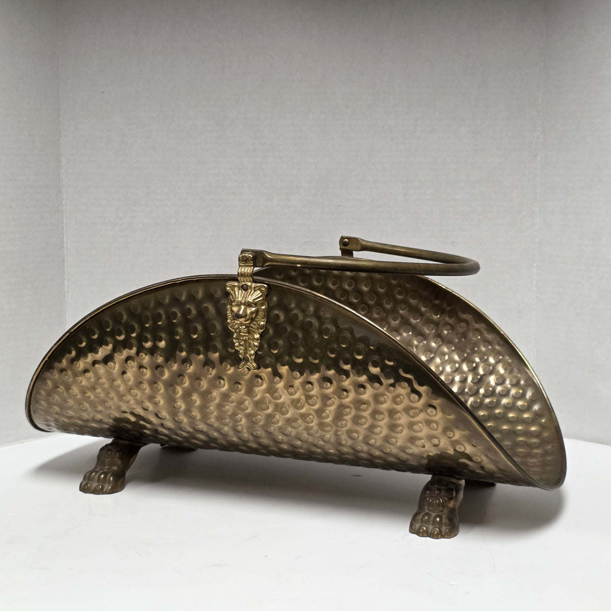 Ornate brass fireplace log holder with lion heads and paw feet
