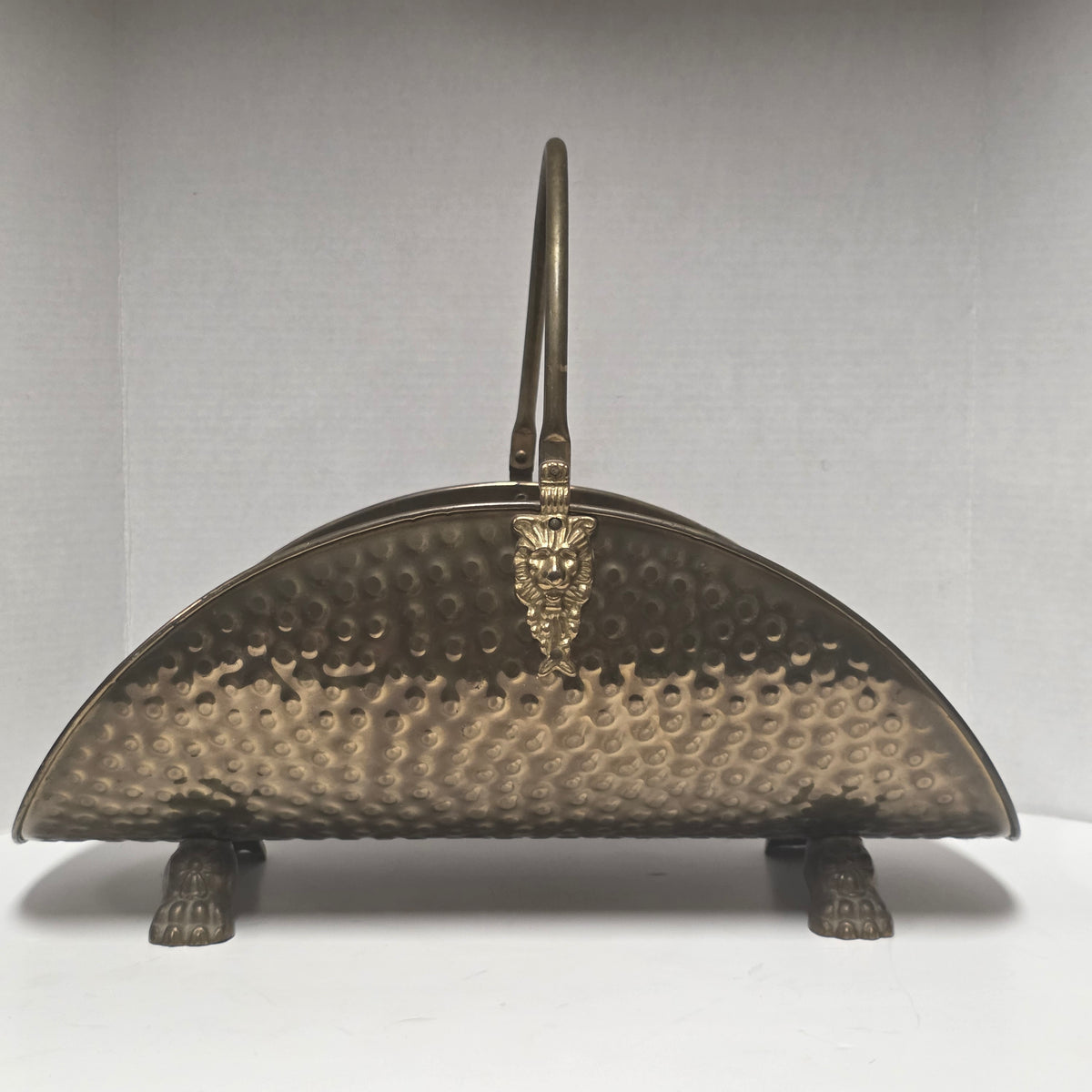 Ornate brass fireplace log holder with lion heads and paw feet
