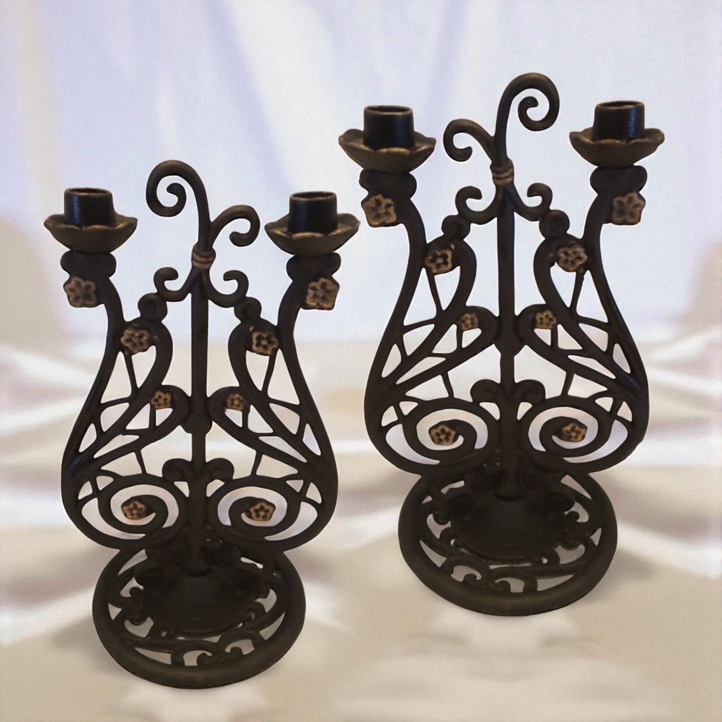 Two ornate black metal candle holders on a white background