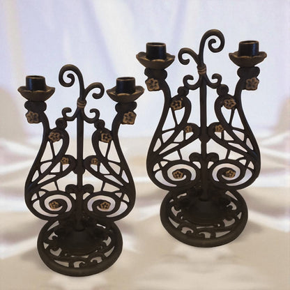 Two ornate black metal candle holders on a white background