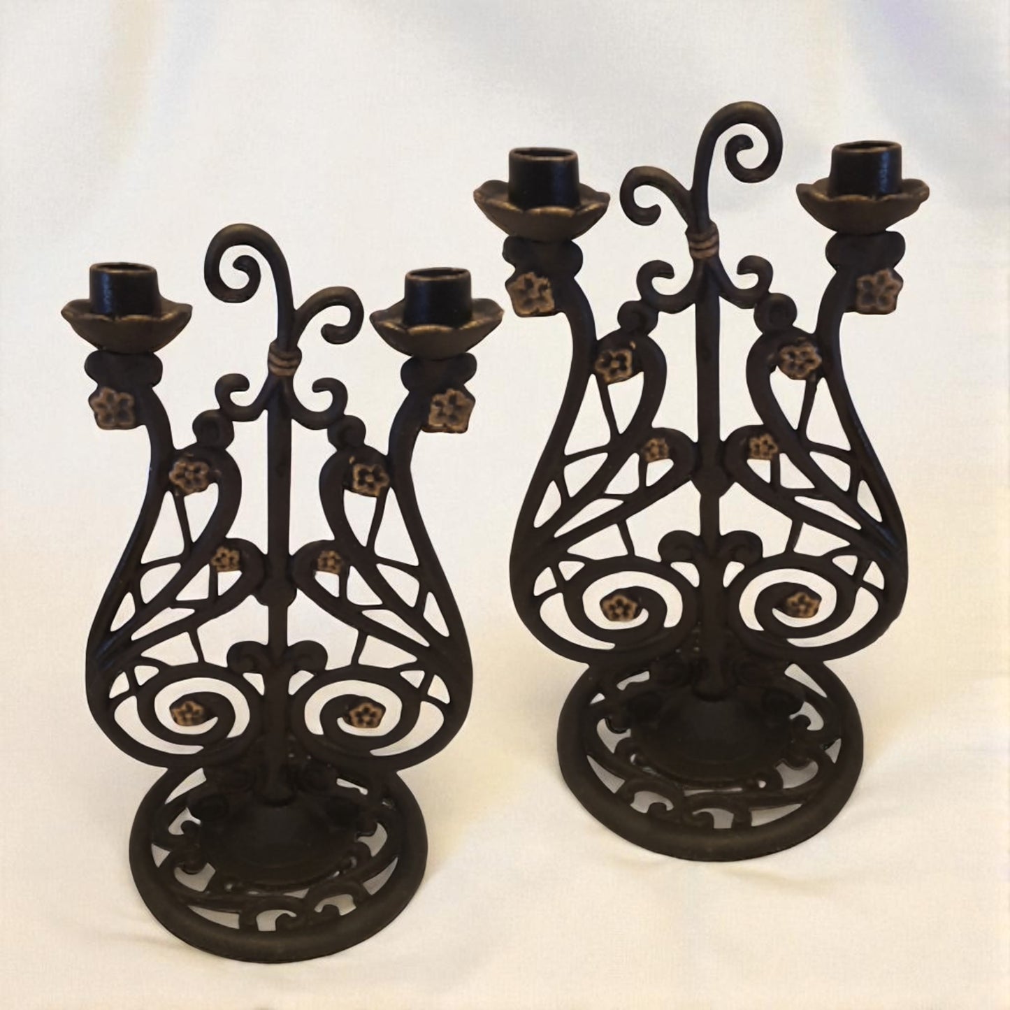 Two black metal candle holders with intricate designs on a white background