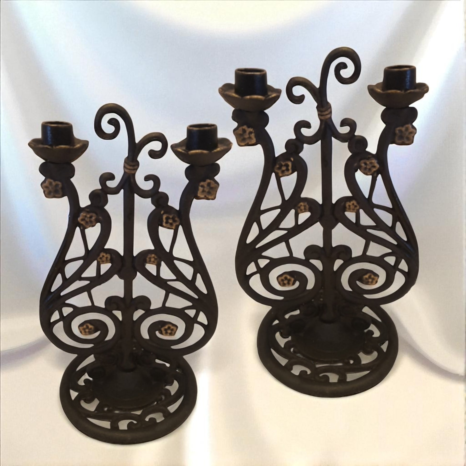 Two ornate black metal candle holders on a white background