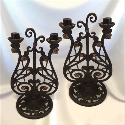 Two ornate black metal candle holders on a white background