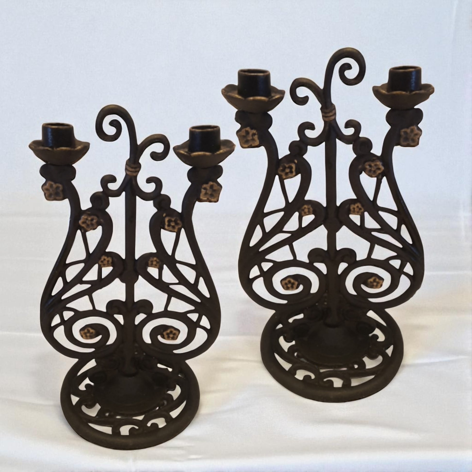 Two ornate black metal candle holders on a white background
