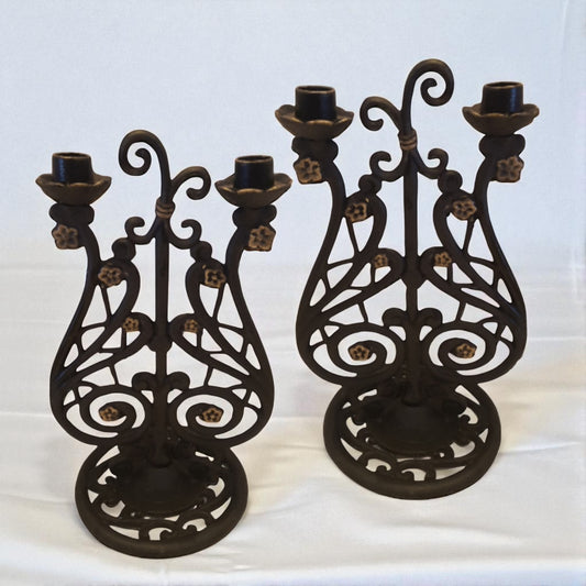 Two ornate black metal candle holders on a white background