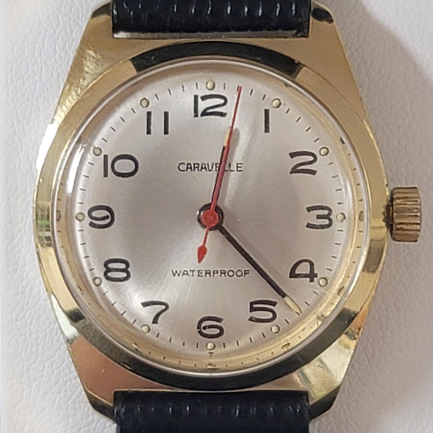 Wristwatch with gold case and black strap on a white background