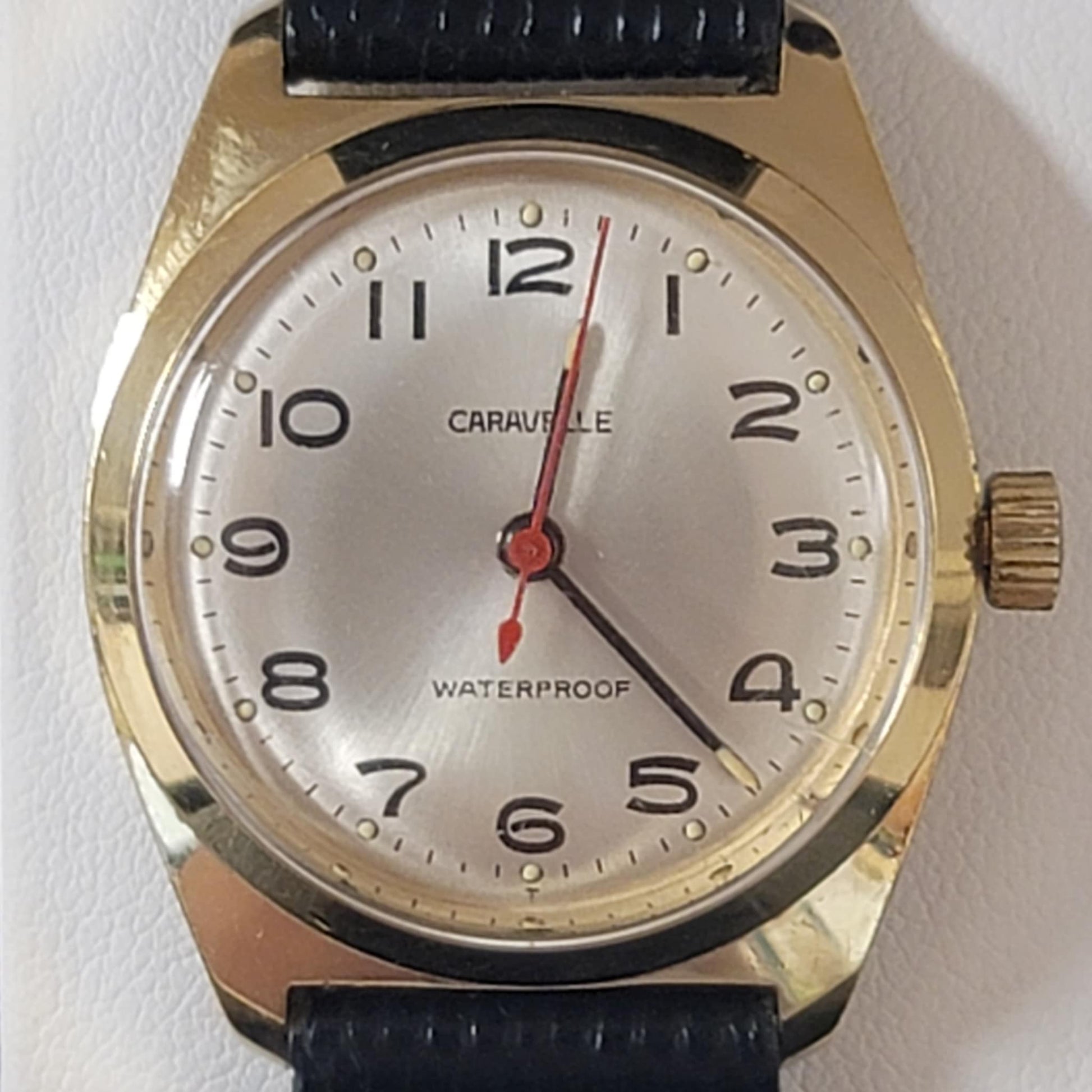 Wristwatch with gold case and black strap on a white background