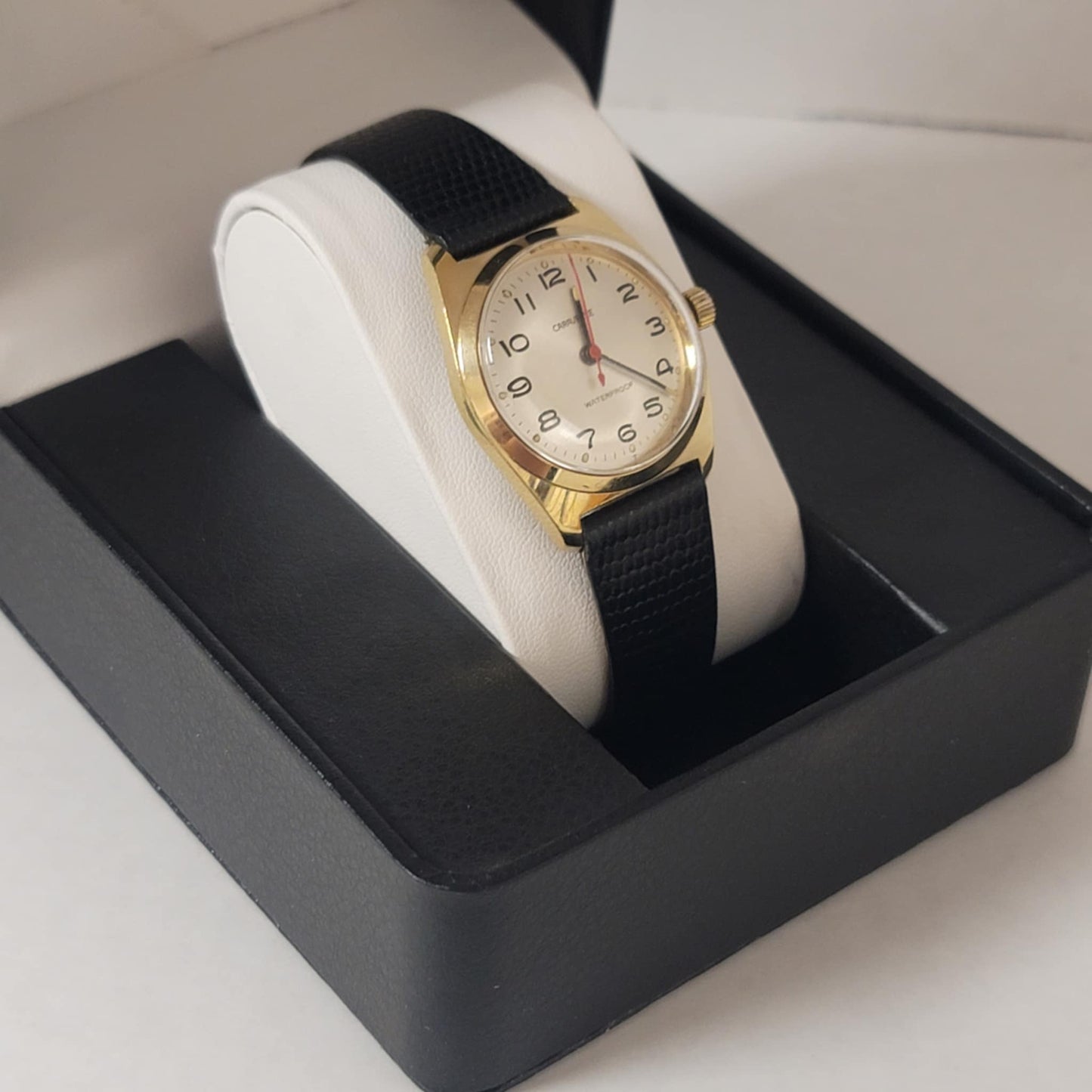 Gold wristwatch with black strap in a display case