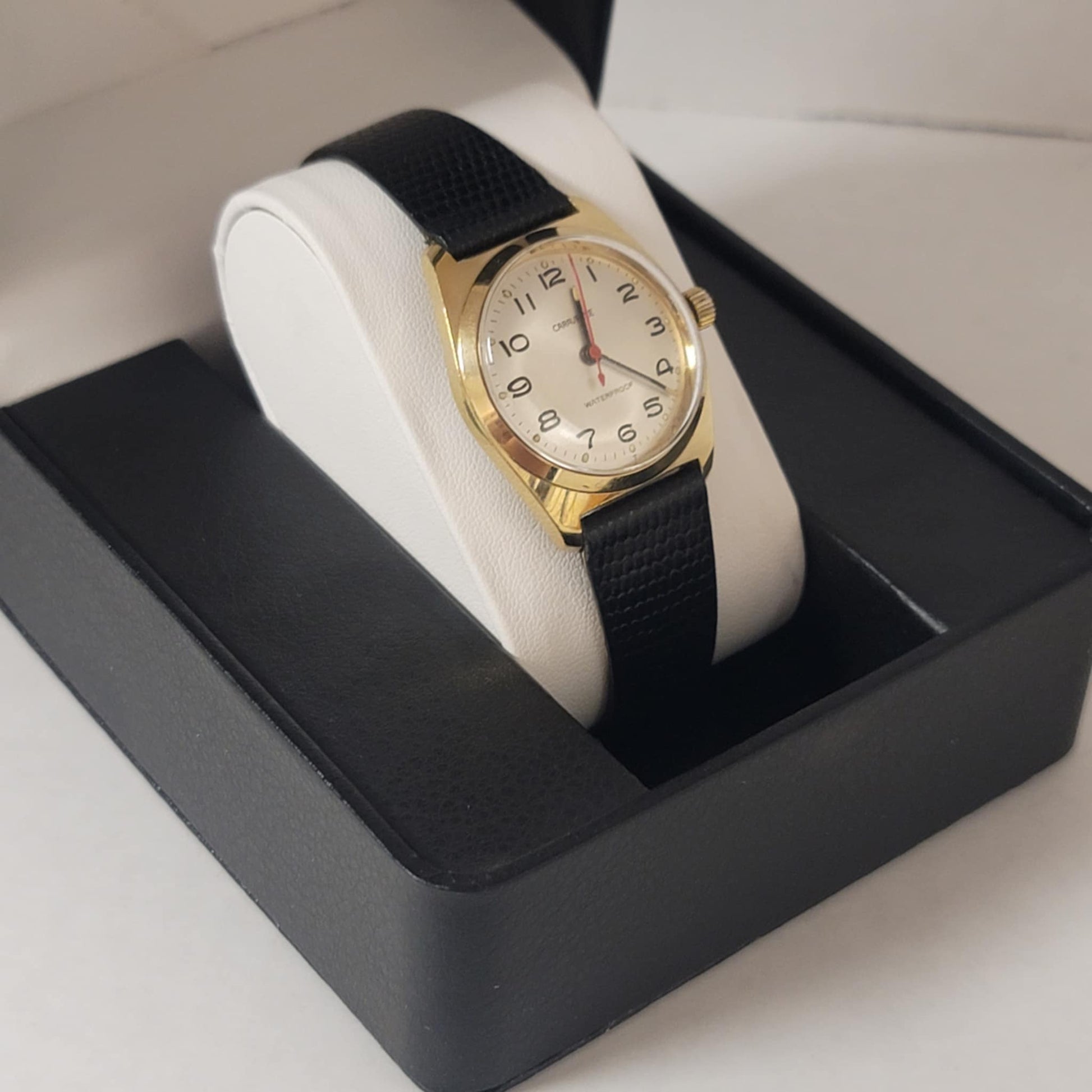 Gold wristwatch with black strap in a display case