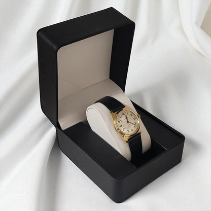 Gold watch with black strap in a black box on a white background