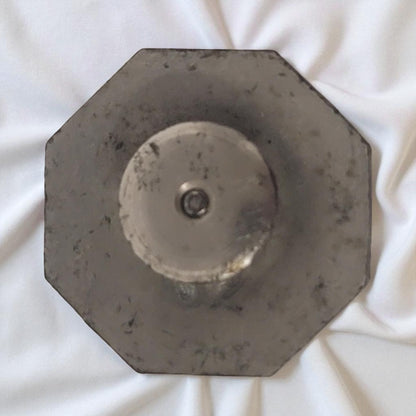 Hexagonal metal object on a white fabric background