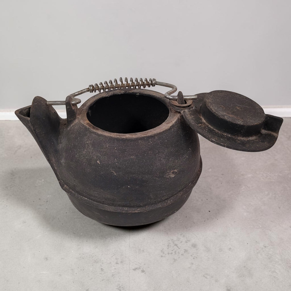 Vintage No. 16 cast iron kettle with swing lid for wood stove humidifying and rustic décor.
