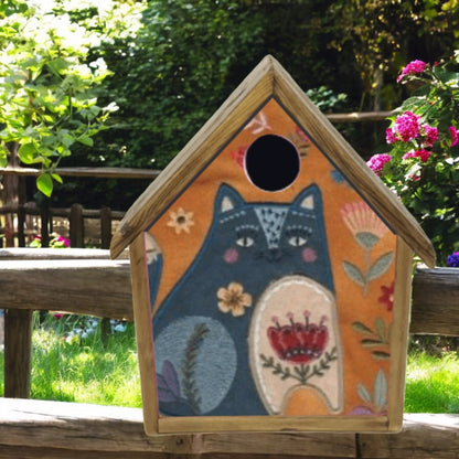Decorative birdhouse with a fox design on a wooden fence