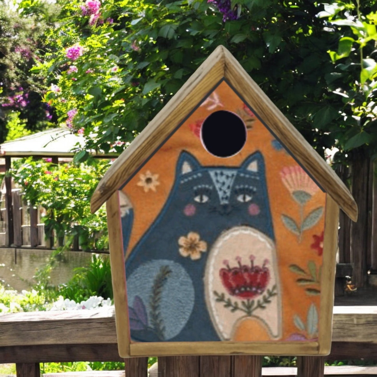 Decorative birdhouse with a cat design in an outdoor setting