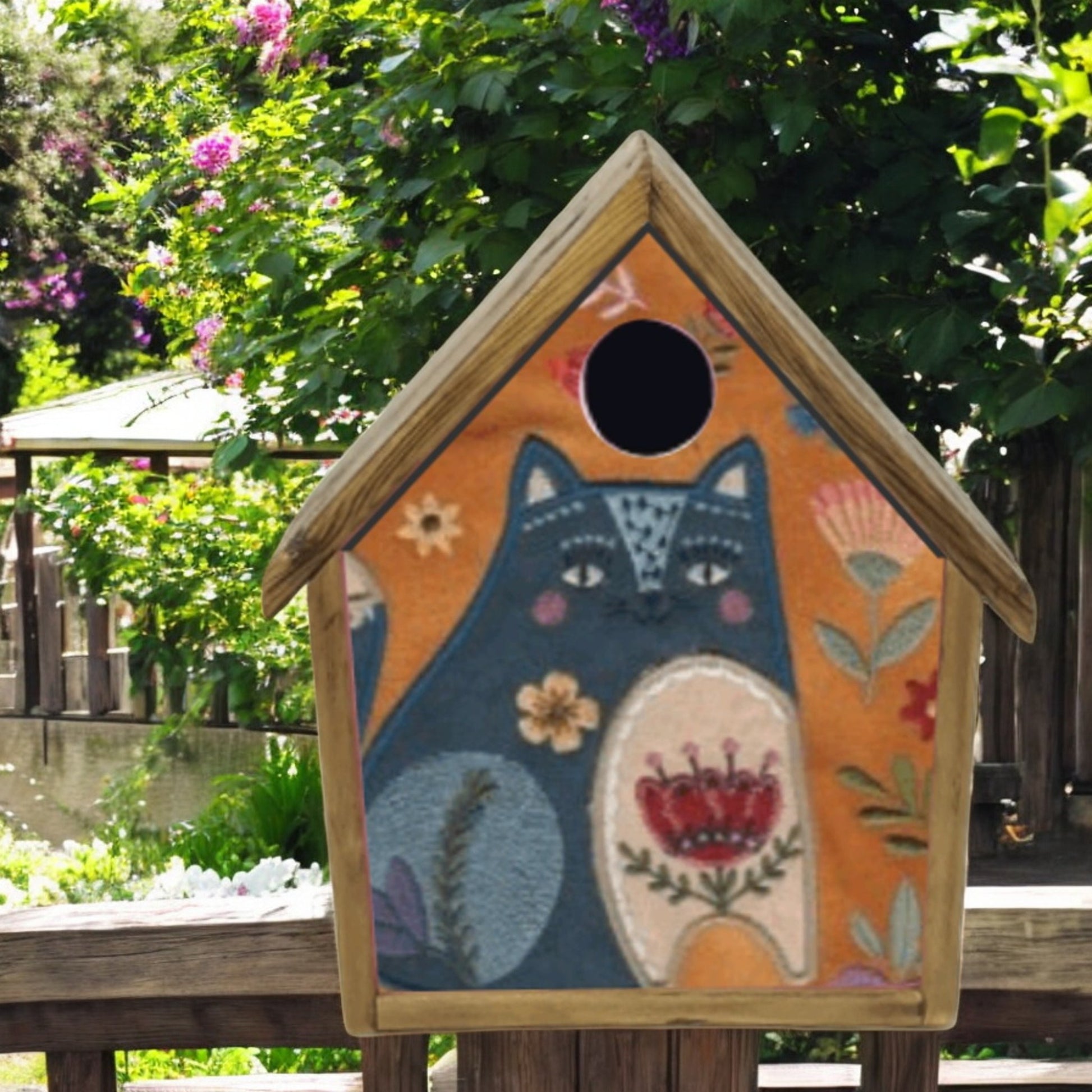 Decorative birdhouse with a cat design in an outdoor setting