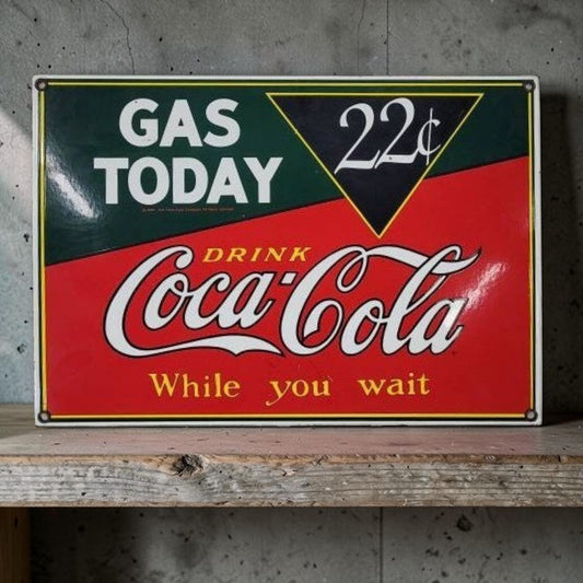 Vintage-style Coca-Cola sign on a wooden surface with a concrete wall background