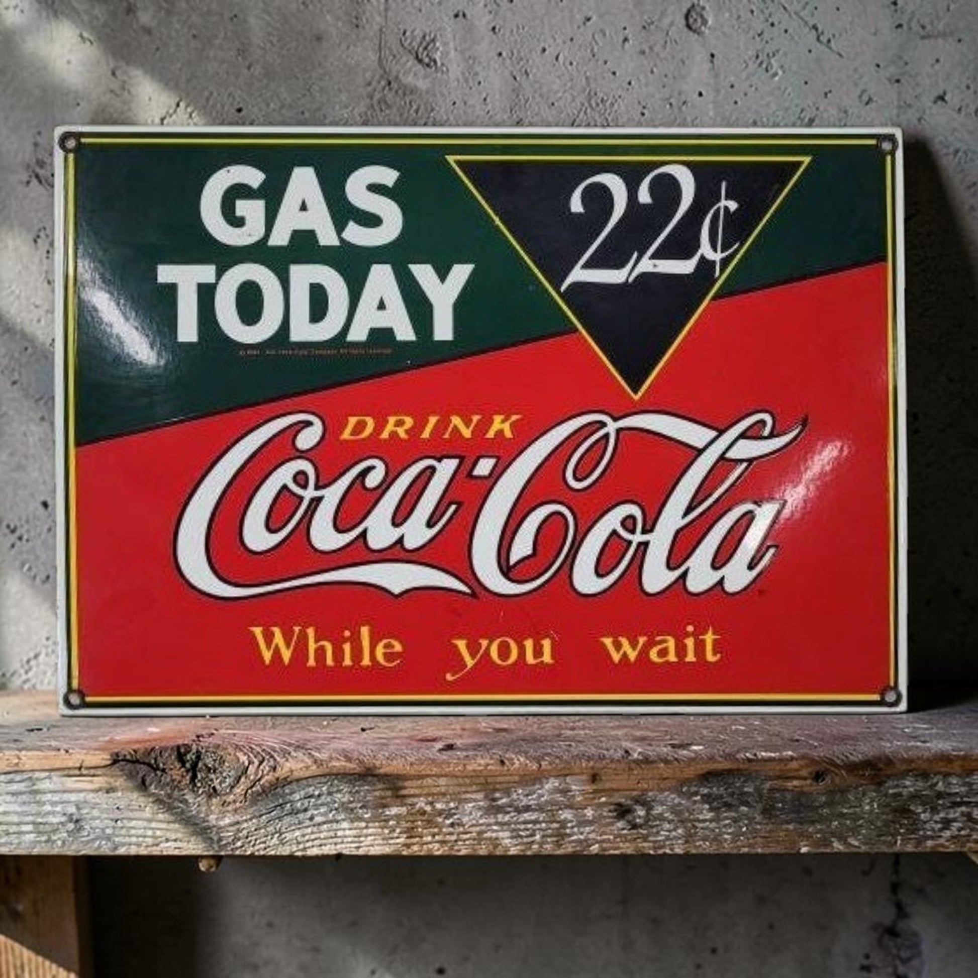 Vintage-style Coca-Cola sign on a wooden surface with a concrete wall background