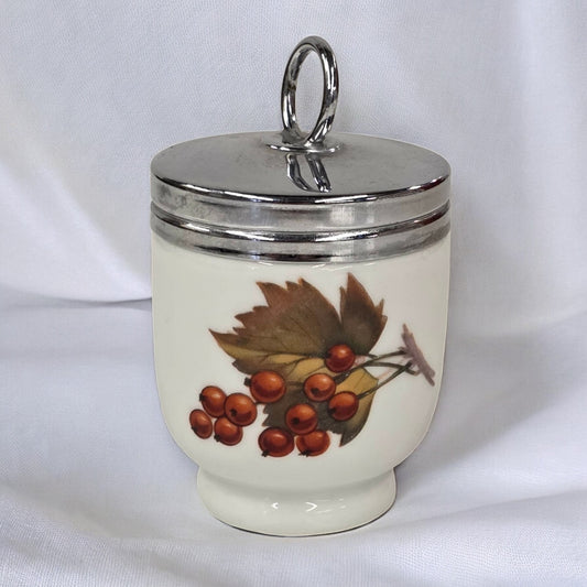 Decorative ceramic jar with silver lid and autumn leaf design on a white background