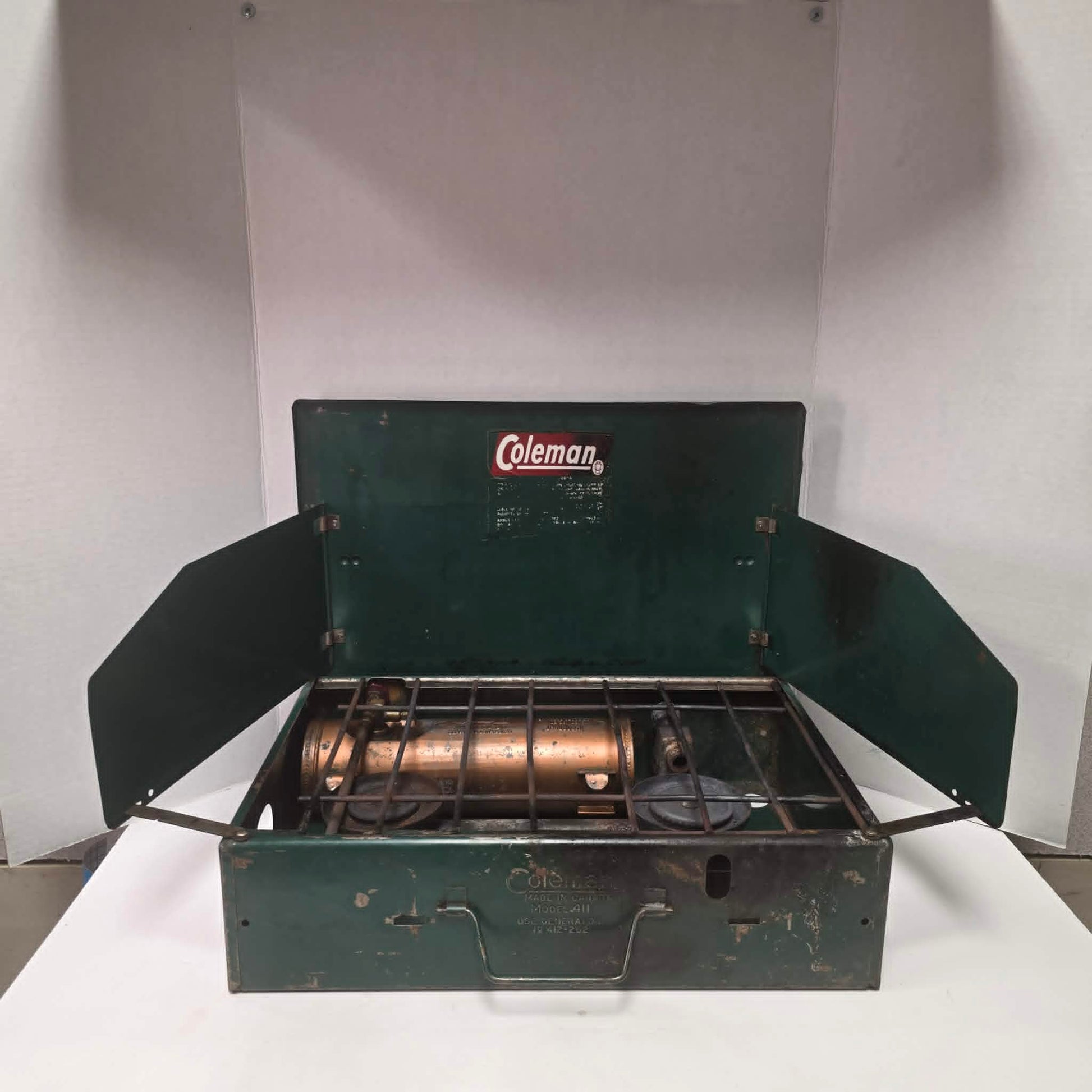 Vintage Coleman Model 411 Canadian suitcase camp stove with copper-colored fuel tank.
