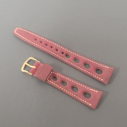 Pink leather watch strap with gold buckle on a gray background