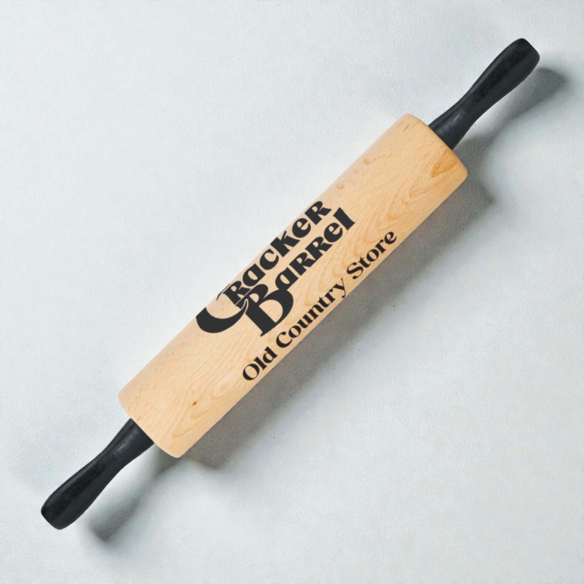 Wooden rolling pin with 'Crafter Barrel Old Country Store' branding on a light gray background