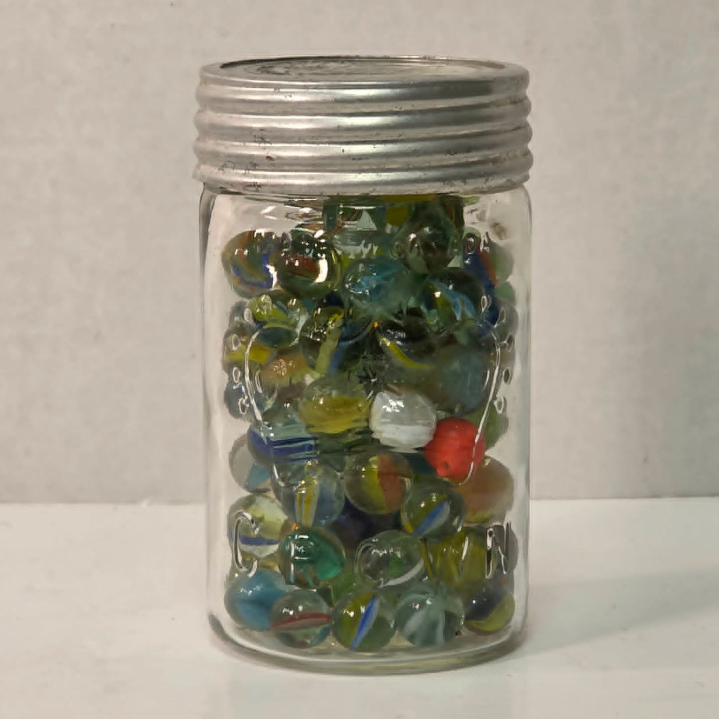 Antique Crown Sealer jar packed with unsorted vintage marbles collected over the years.