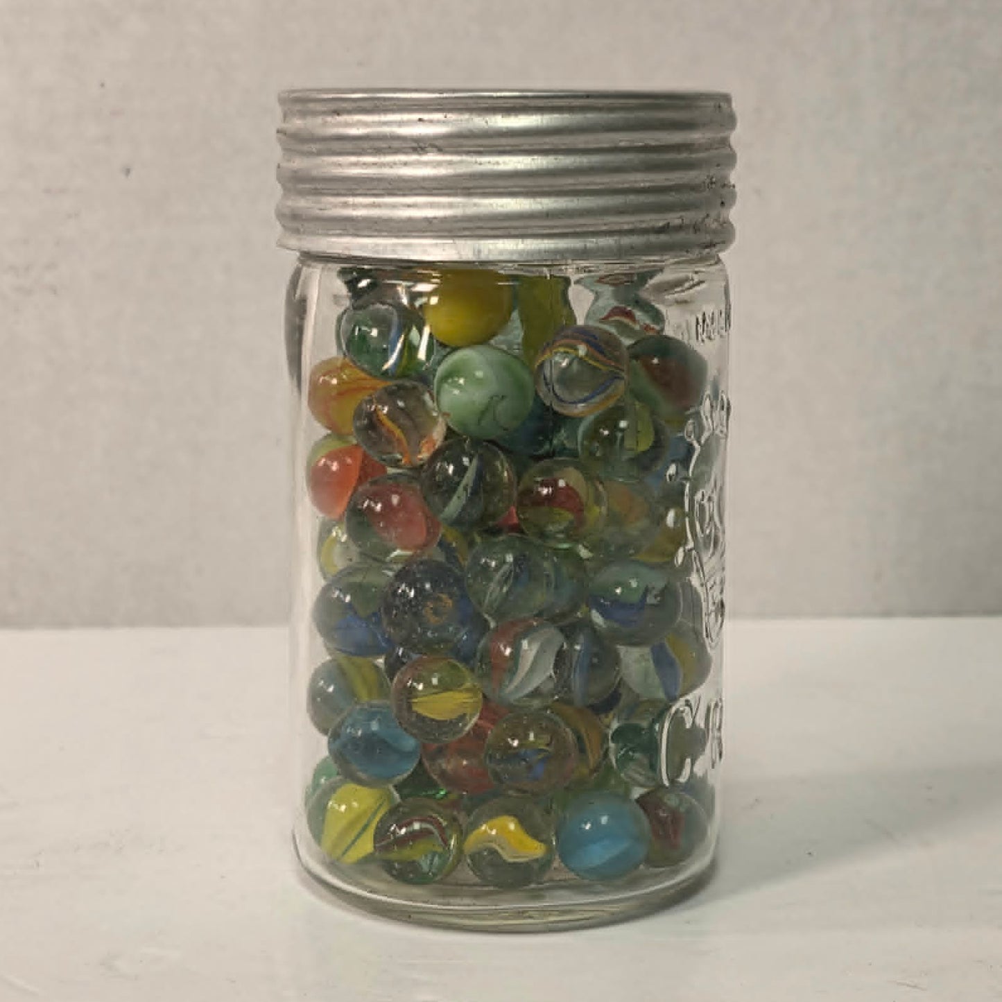 Antique Crown Sealer jar packed with unsorted vintage marbles collected over the years.