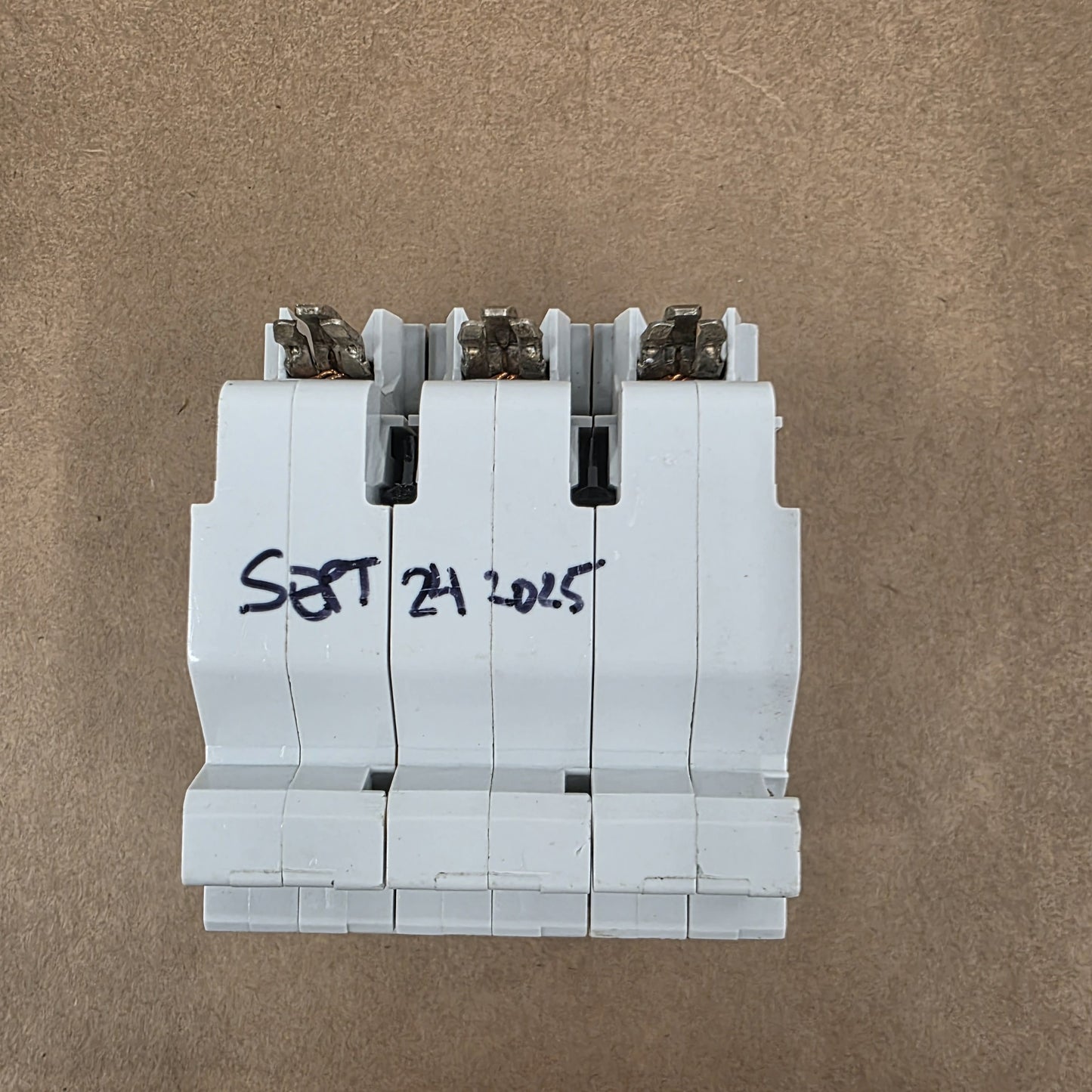 Stack of white plastic components with 'SEPT 24 2023' written on a brown background